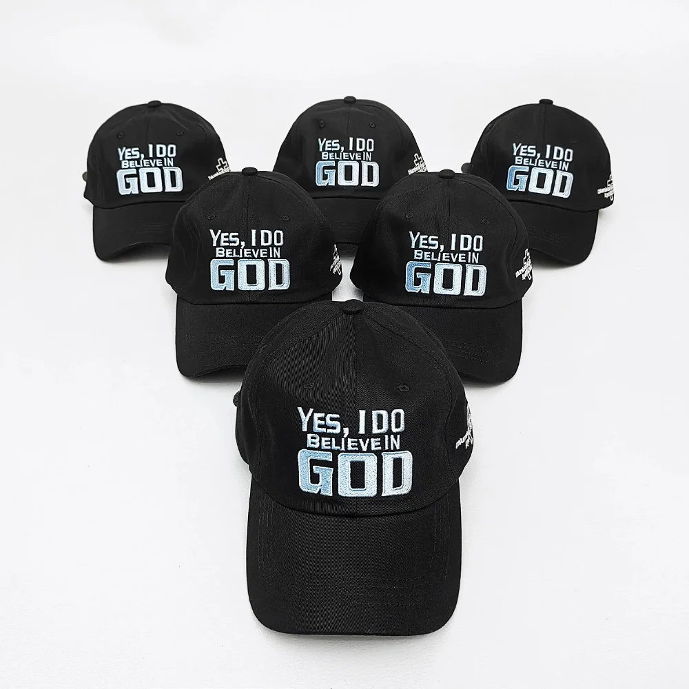 Black cotton baseball cap with light blue embroidered 'YES, I DO BELIEVE IN GOD' text