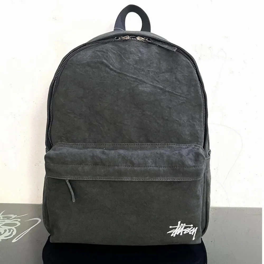 Stussy dark gray canvas backpack with front pocket and embroidered logo