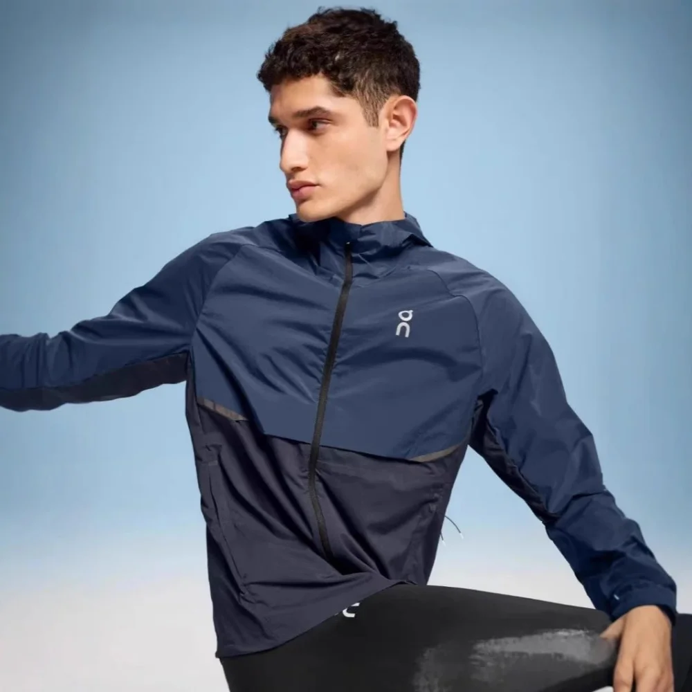 On navy blue windbreaker jacket with black zipper and paneling