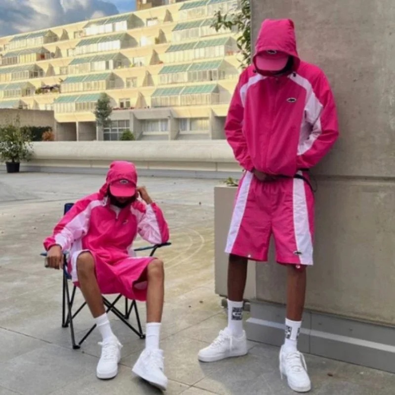Bright pink nylon shorts with white diagonal stripe panels and black waistband