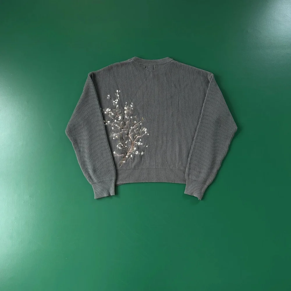Gray ribbed knit sweater with white floral embroidery on back