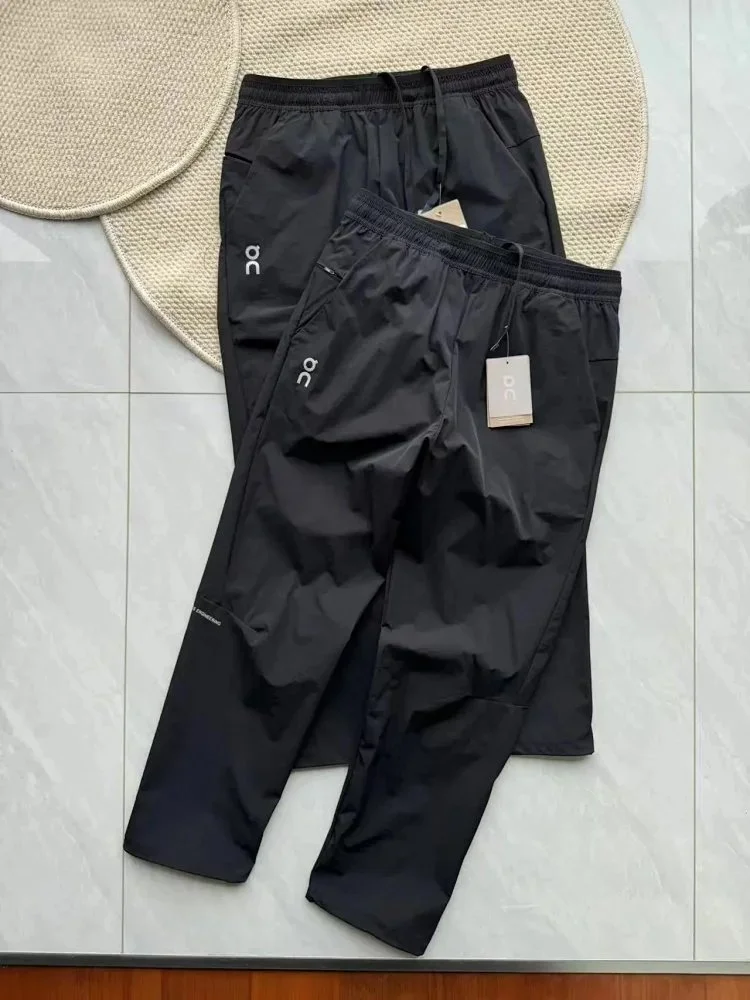On black lightweight nylon jogger pants with elastic waist and side logo