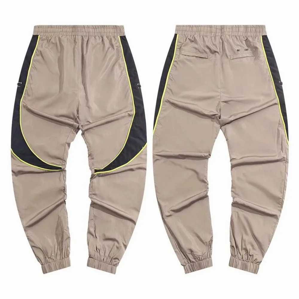 Khaki nylon track pants with black side panels and neon green piping