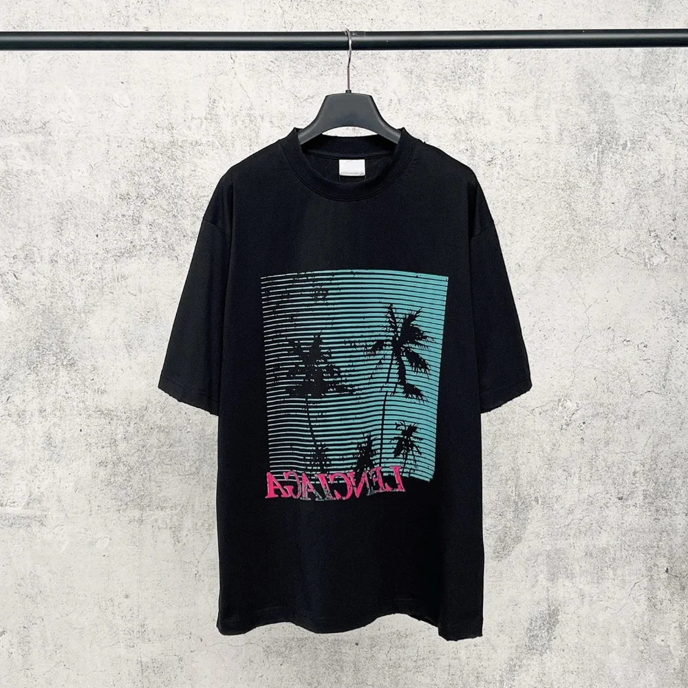 Black oversized t-shirt with teal striped palm tree graphic and pink reversed text