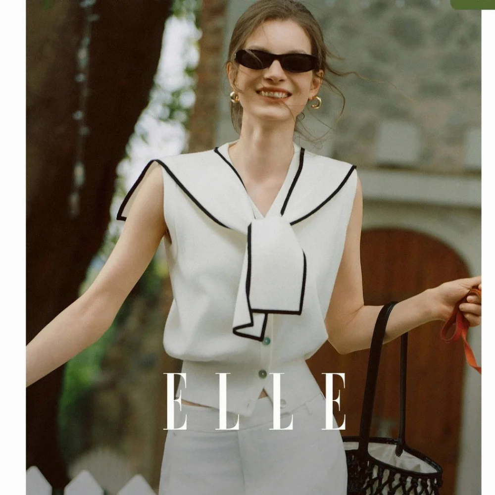 white sleeveless knit top with black trim navy collar and front bow