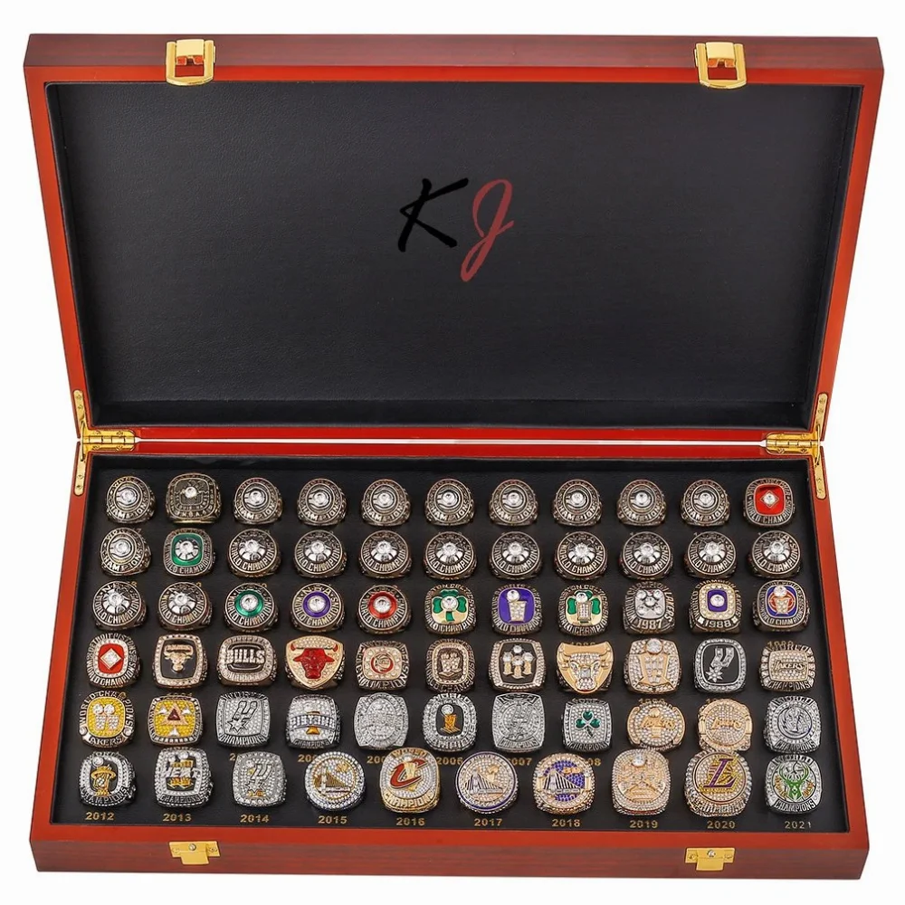 Gold and silver championship rings with gemstones and team emblems in wooden display box